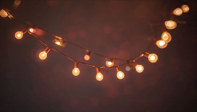 Warm amber string lights casting cozy patio ambiance with glowing filament bulbs and bokeh
