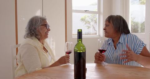 Senior Female Friends Sharing Wine and Conversation at Home