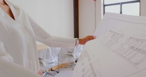 Architect Examining Blueprint in Contemporary Office
