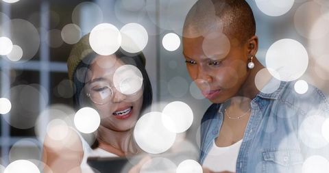 Two colleagues collaborating over smartphone with soft bokeh light overlays