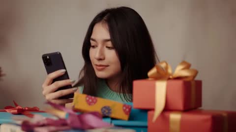 Woman Celebrating with Gift Boxes Using Smartphone at Home