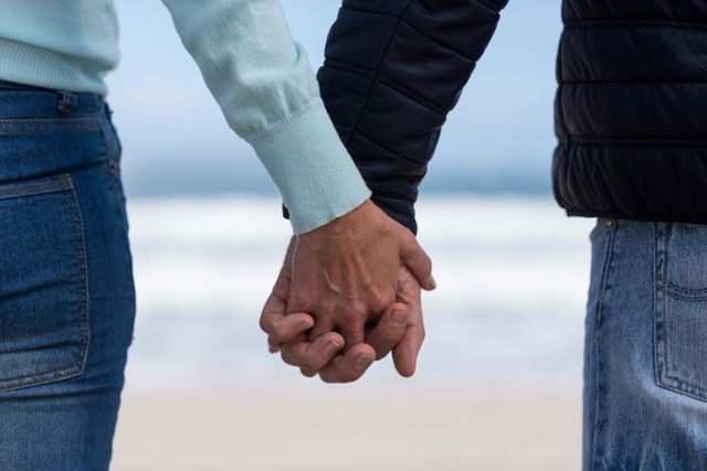 Close-up of couple standing with holding hands on the beach