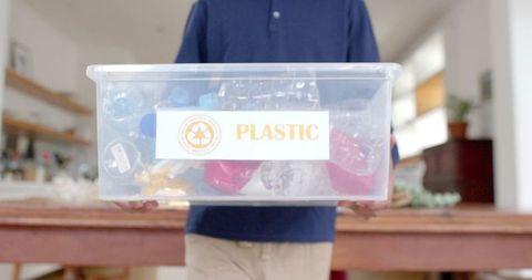 Child Holding Plastic Recycling Bin in Home Kitchen