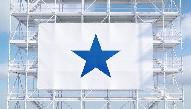 Giant white banner featuring blue star on industrial scaffolding against blue sky