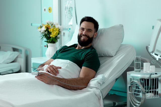 Portrait of bearded caucasian male patient sitting up in hospital bed smiling. Medical services, hospital and healthcare concept.
