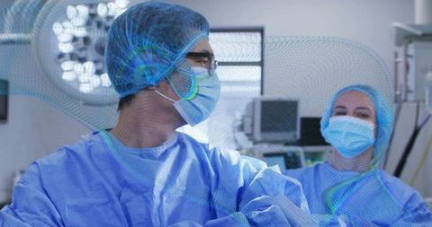 Surgeon and nurse collaborating in operating room wearing ppe and sterile blue scrubs