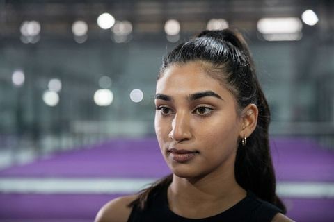 Indian female athlete looking left on purple indoor court wearing hoop earrings