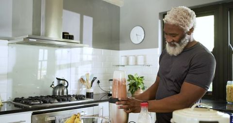 Senior African American Man Making Healthy Smoothie in Modern Kitchen