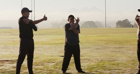 Men stretching on dewy field at sunrise preparing for team fitness training