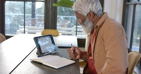 Senior Man Using Tablet for Writing Inspiration in Modern Office