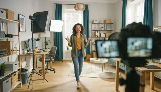 Female Content Creator Presenting in Home Studio with Camera, Softbox Lighting, Casual