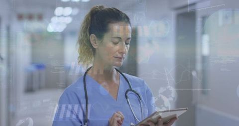 Female nurse using tablet with medical analytics overlays in hospital corridor telemedicine
