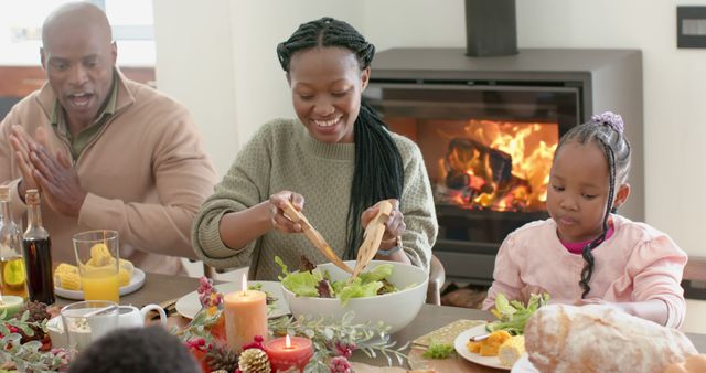 Family gathering for a festive holiday meal by a warm fireplace. Mother serving fresh salad, father and children enjoying quality time. Ideal for content on holiday celebrations, family togetherness, cozy home dining, and festive gatherings.