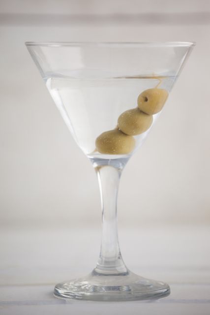 Close up of olives in martini glass on table