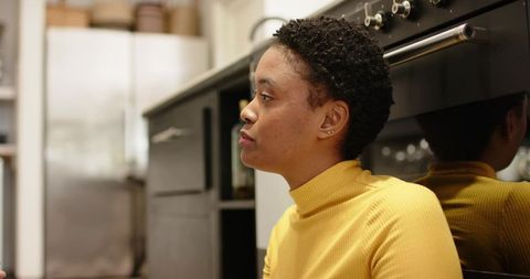 Contemplative Woman in Modern Kitchen by Black Oven