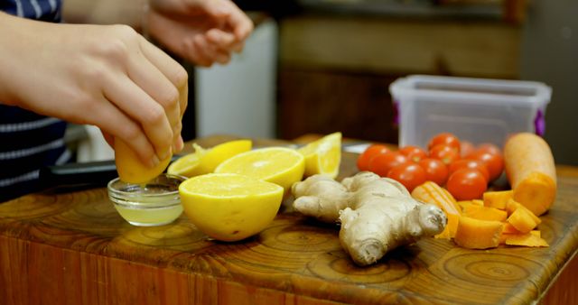Caucasian woman wearing apron and squeezing lemon with vegetables in kitchen. Domestic life, food and lifestyle.