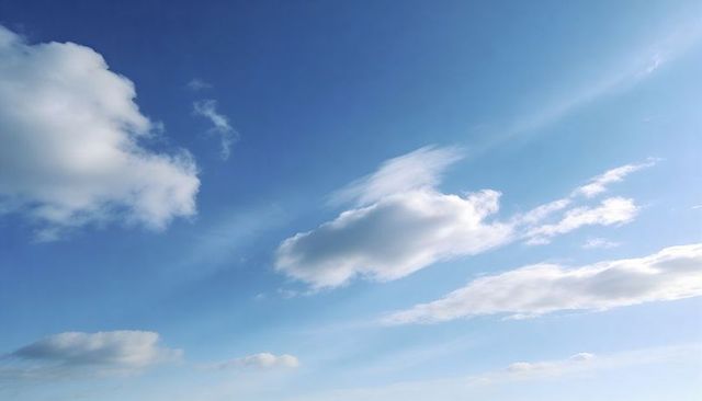 Sunlit fluffy cumulus cloud floating across expansive blue sky with soft cirrus streaks