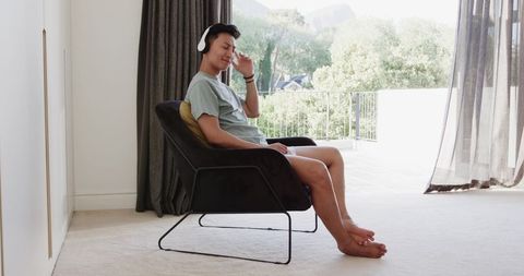 Man Relaxing in Chair with Headphones by Sunlit Terrace