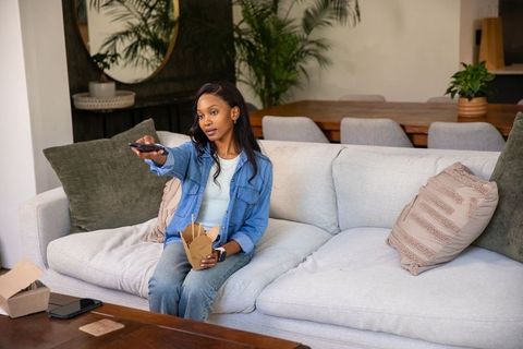 African American Woman Enjoying Takeout in Cozy Living Room