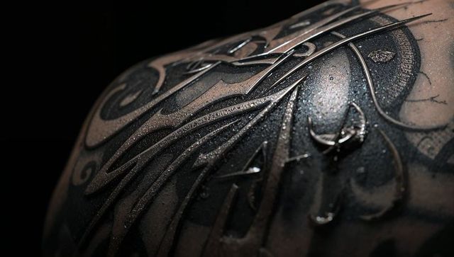 Wet Enigmatic Monochrome Tattoo on Shoulder in Dark Surrounding