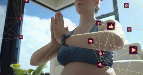 Pregnant woman practicing prenatal yoga in sunny living room with wearable tracker icons