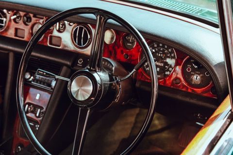 Vintage car interior with wooden dashboard focus and classic steering wheel