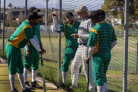 Cricket players listening to coach during net practice showing teamwork and focus
