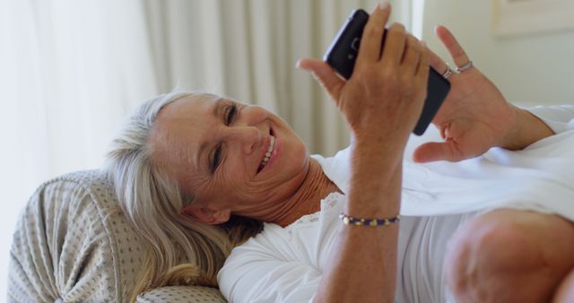 Senior Woman Smiling and Reading on Smartphone While Relaxing in Bed - Download Free Stock Images Pikwizard.com