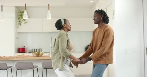 African American Couple Sharing Tender Moment in Modern Minimalist Kitchen Expecting Baby
