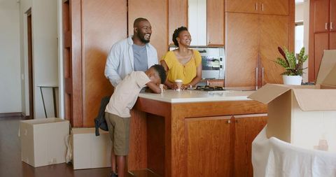 African American Family Laughing While Unpacking at Kitchen Island After Move