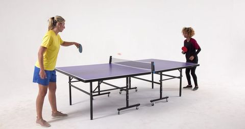 Two women playing ping pong in studio environment
