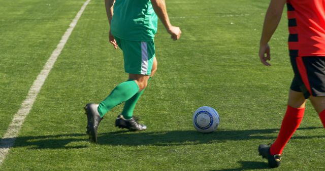 Soccer players are dribbling the ball during a match on a green field. This action is taking place in real-time competition, highlighting teamwork and athletic skills. Useful for sports promotions, team dynamics visuals, and youth soccer advertisements.