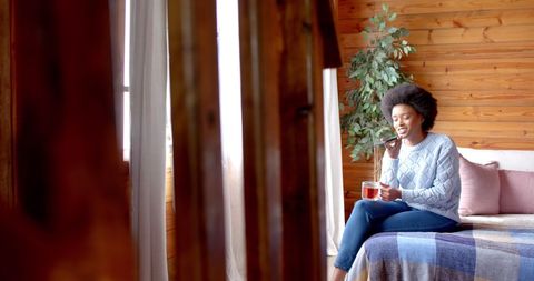 Joyful African American Woman Relaxing with Tea and Phone Call in Cozy Home - Download Free Stock Images Pikwizard.com