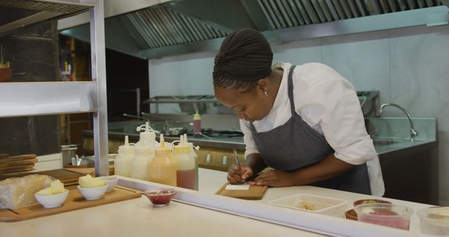 African American female chef writing in modern commercial kitchen - Download Free Stock Images Pikwizard.com