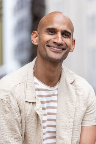 Smiling african american man in 30s wearing beige overshirt and striped tee urban portrait