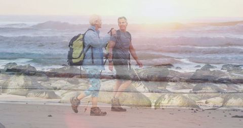 Couple Hiking on Beach at Sunrise with Trekking Poles and Backpacks