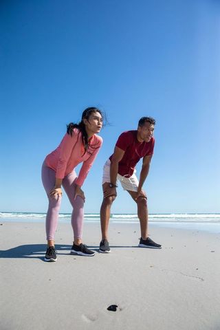 Fit Couple Cooling Down After Beach Run on Sunny Day
