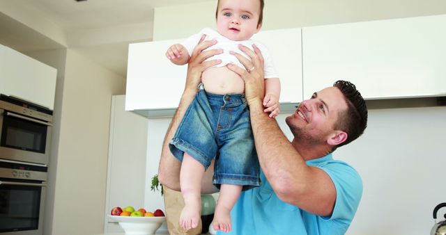 Smiling Father Lifting Baby in Bright Modern Kitchen - Download Free Stock Images Pikwizard.com