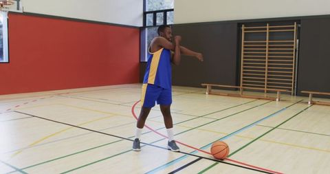 Young Basketball Player Stretching in Gym Before a Game