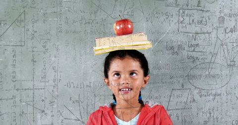Girl Balancing Books and Apple Against Chalkboard Equations - Download Free Stock Images Pikwizard.com