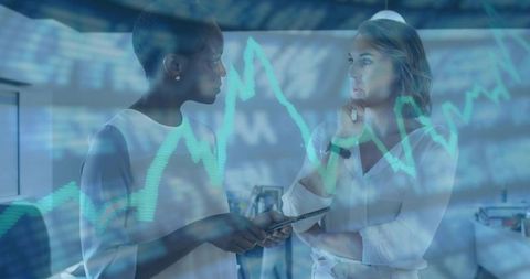 Dynamic Businesswomen Analyzing Market Data on Tablet