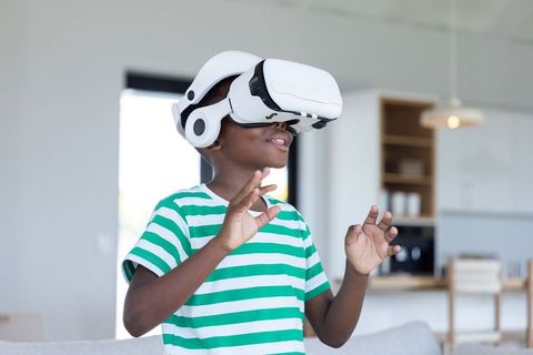 African american boy exploring virtual reality with white vr headset in modern home