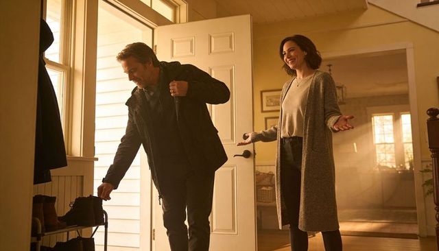 Couple entering cozy home greeting returning partner removing shoes near sunlit door