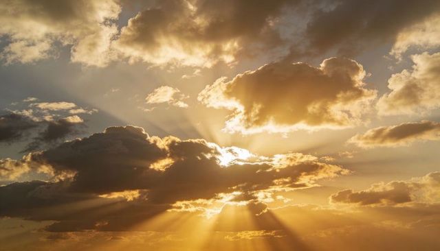 Golden sunbeams breaking through dramatic clouds at sunset