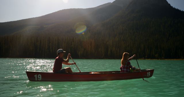 Couple enjoying a morning paddle on a peaceful mountain lake. Ideal for nature, adventure, and outdoor activity promotions. Perfect for travel agency advertisements, outdoor gear retailers, and lifestyle blogs.