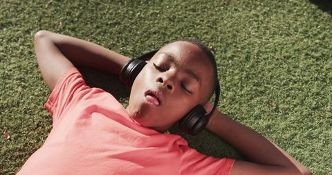 Teenage Boy Relaxing with Headphones on Green Turf