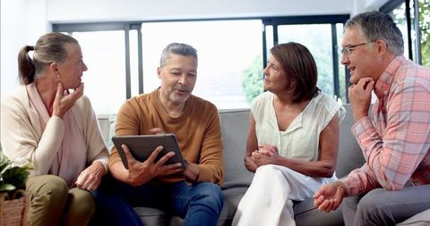 Mature Friends Enjoying Content on Tablet in Relaxed Home Environment