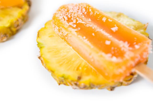 Close-up view of a pineapple ice lolly placed on pineapple slices. Perfect for use in summer-themed promotions, tropical fruit advertisements, dessert recipes, and refreshing snack ideas.