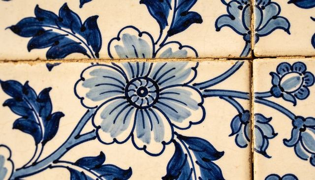 Hand-painted blue delft-style ceramic tiles close-up showing floral motif, grout detail