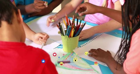 Children drawing together at craft table sharing colored pencils and creative collaboration